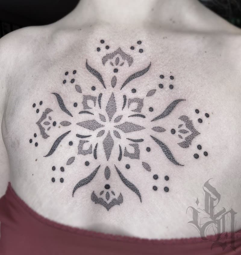Sierlijke dotwork mandala tattoo op de borst.