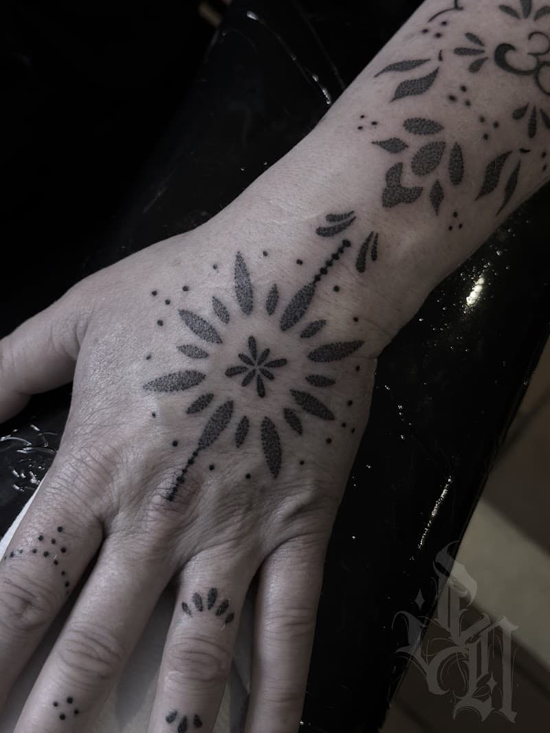 Sierlijke ornamentele dotwork tattoo op hand, vingers en pols.