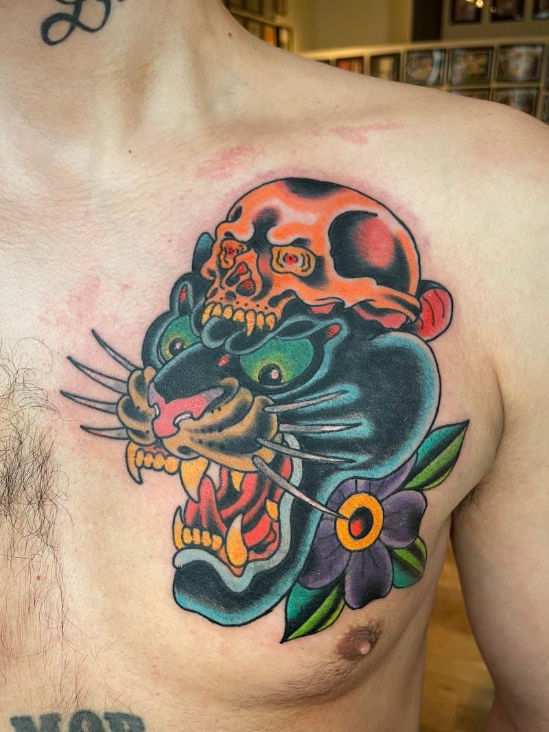 Traditionele panterkop met schedel en bloem op de borst.