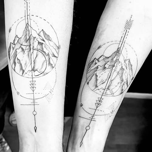 Twee bijpassende geometrische bergtatoeages met cirkels en pijlen op onderarmen.