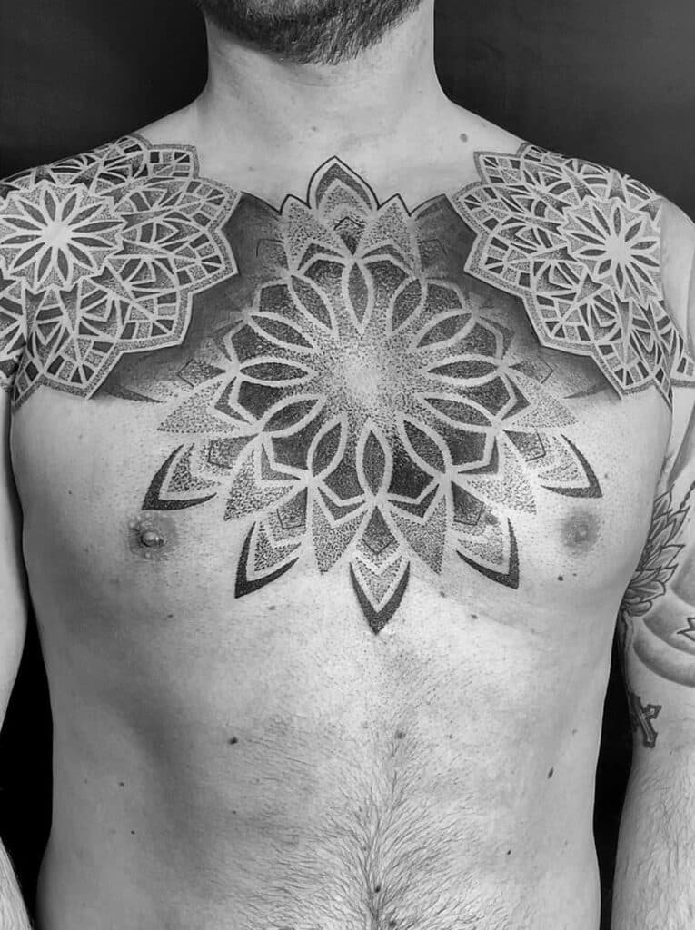 Grote geometrische dotwork mandala tattoo op de borst en schouders.