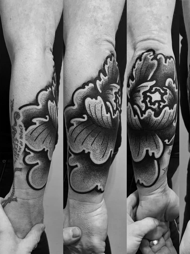 Grote Japanse pioenroos en tekst op onderarm.