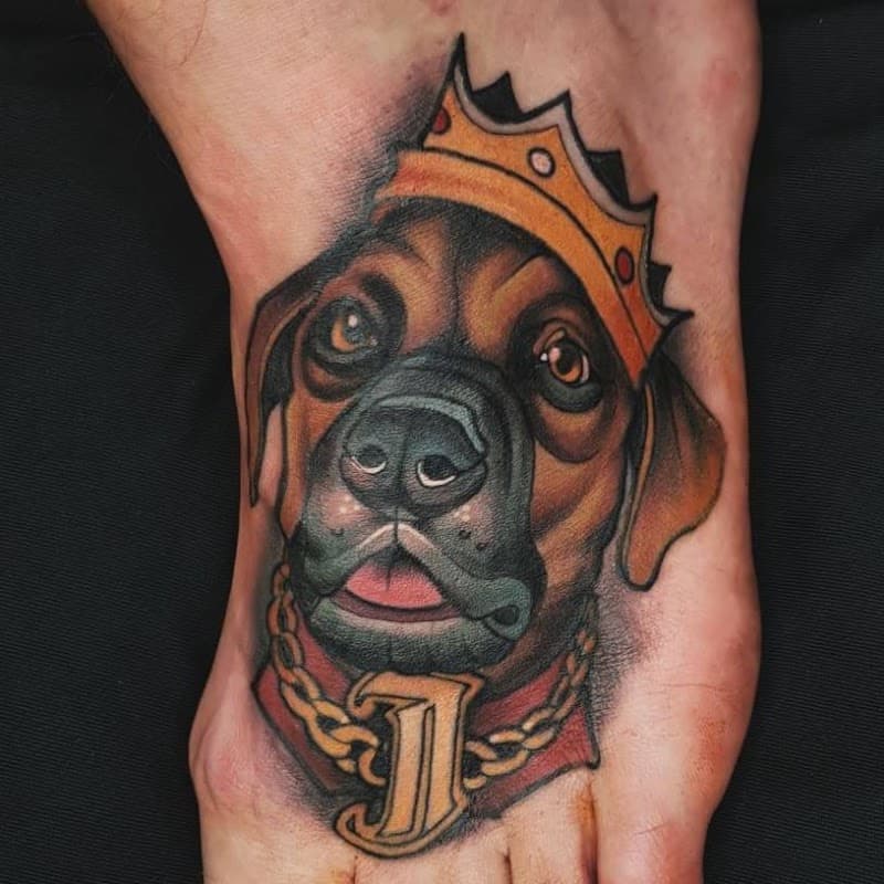 Neo-traditional tattoo van een boxer hond met een kroon en gouden ketting.