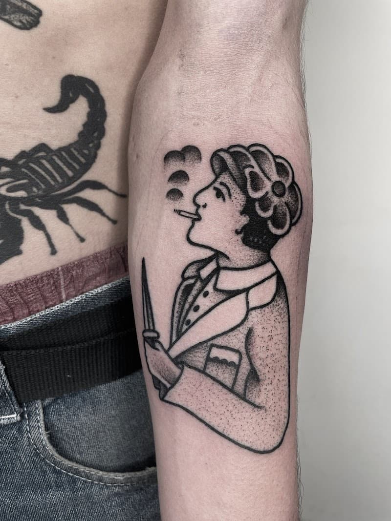 Traditionele zwart-wit tattoo van rokend persoon met mes op onderarm.