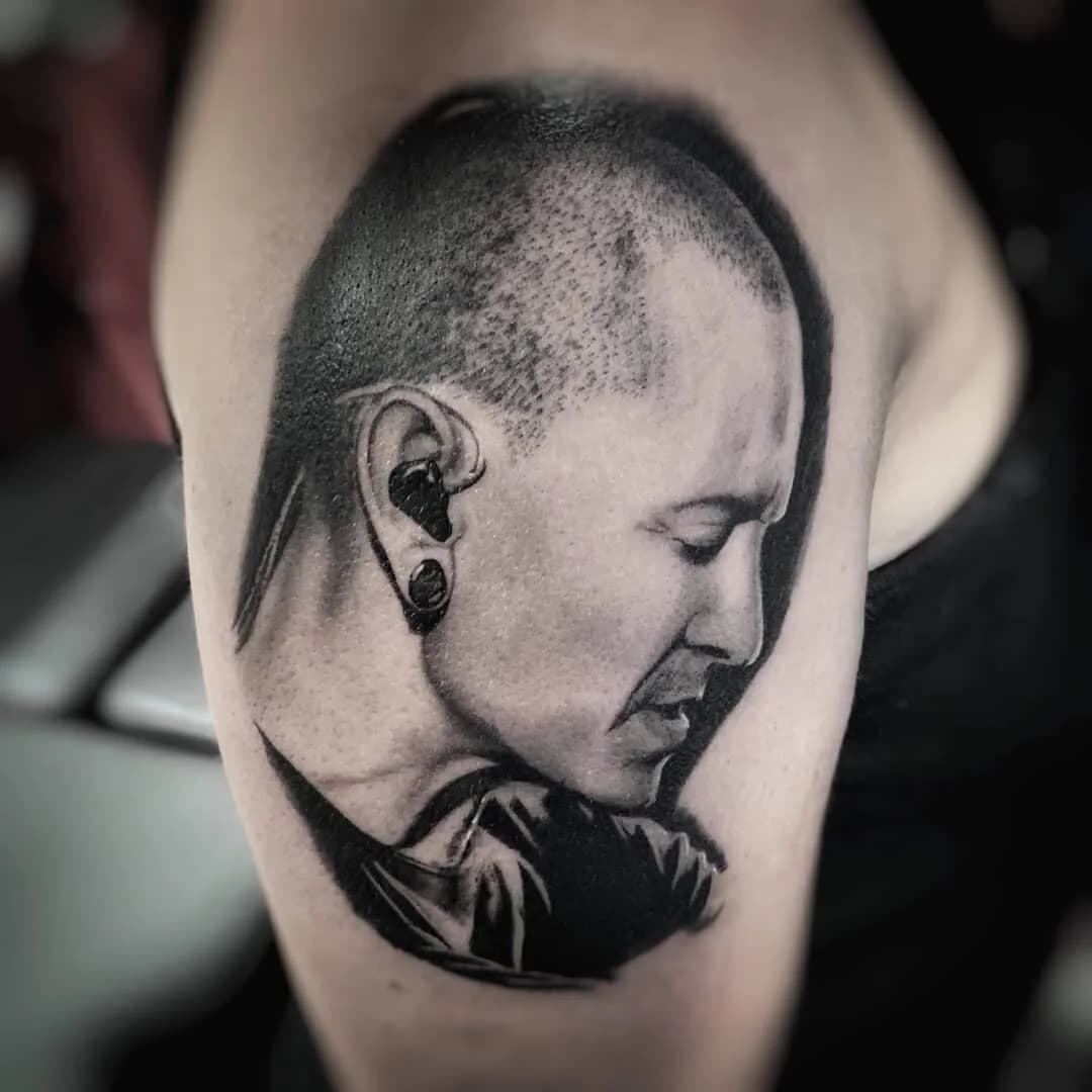 Realistisch portret van Chester Bennington op bovenarm.
