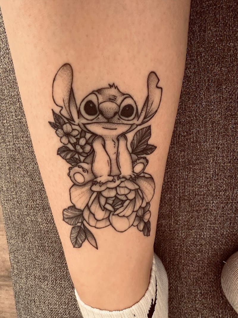 Zwart-wit fineline tattoo van Stitch op een bloem op het onderbeen.