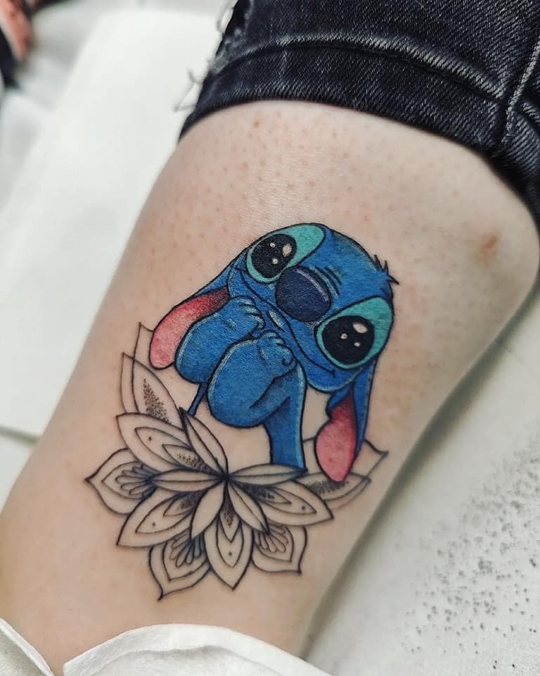 Kleurrijke Stitch tattoo zittend op een zwart-wit mandala bloem.