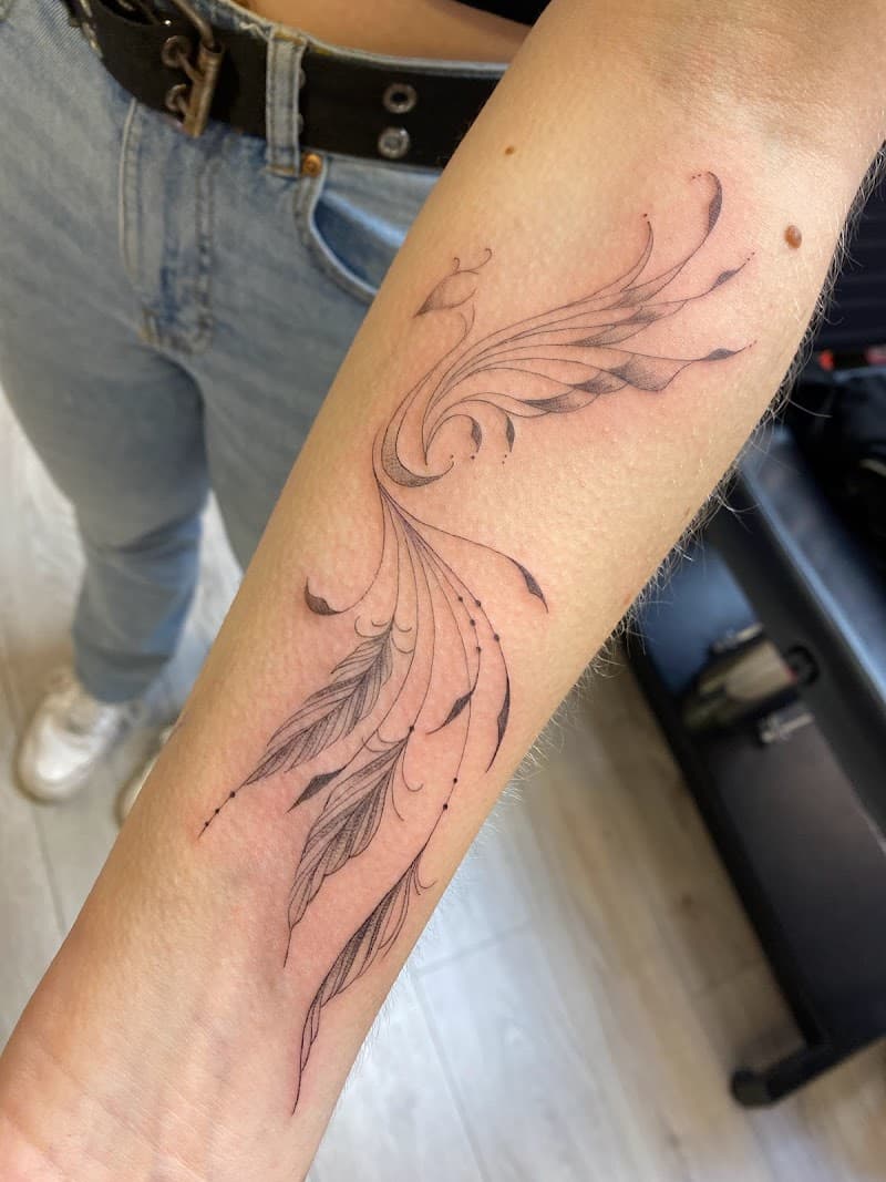 Elegante fineline tattoo van veren en abstracte lijnen op de onderarm.