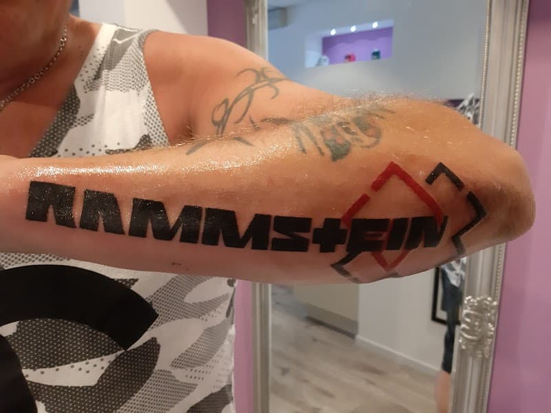 Zwart en rood Rammstein logo en tekst op de onderarm.