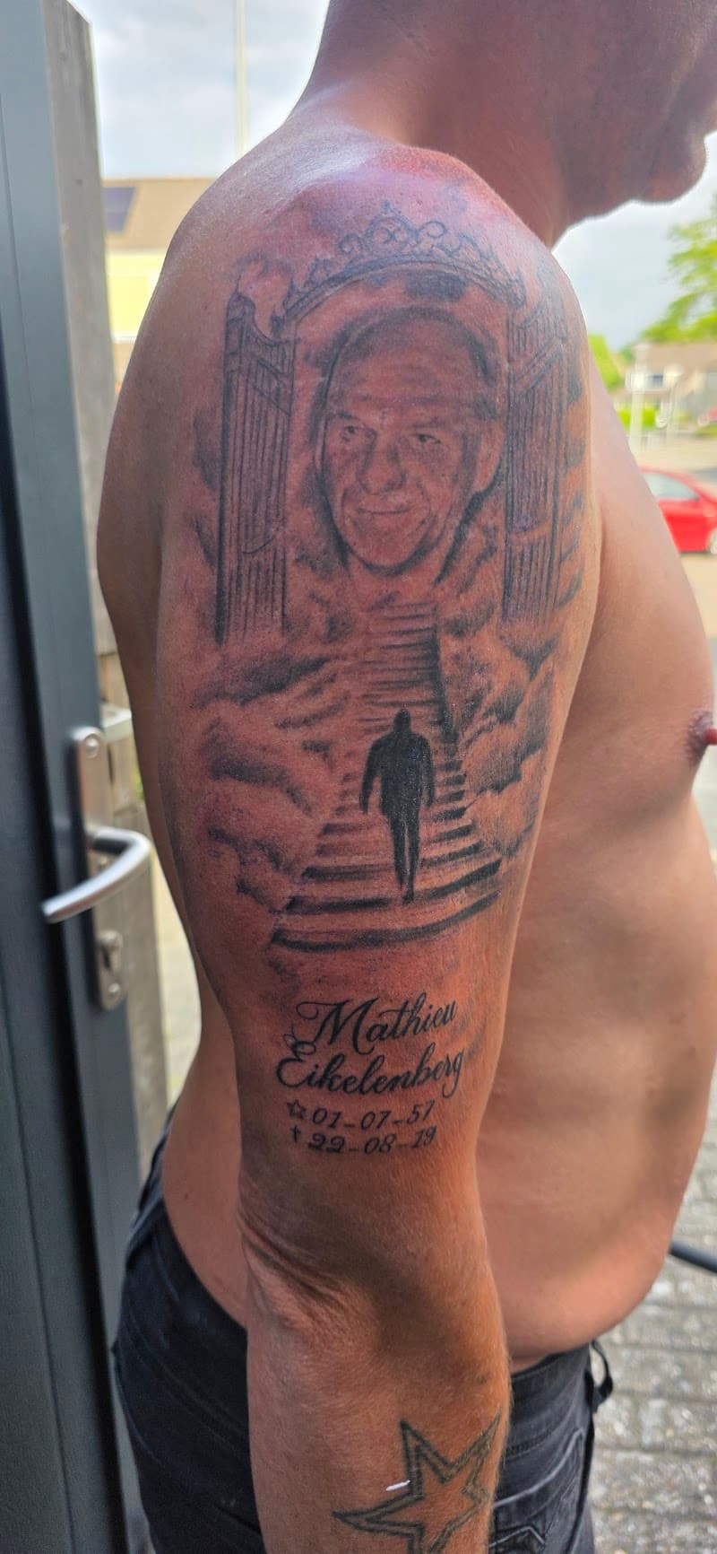 Herdenkingstattoo met portret, hemelpoort en trap op bovenarm.
