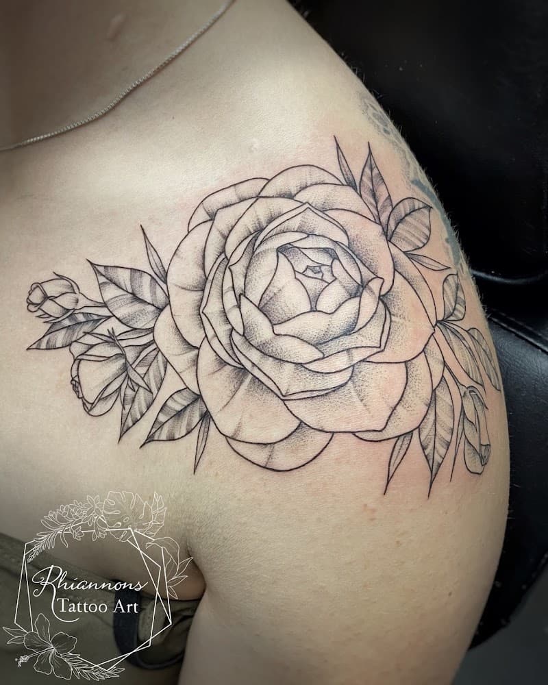 Fineline en dotwork roos met bladeren op de schouder.
