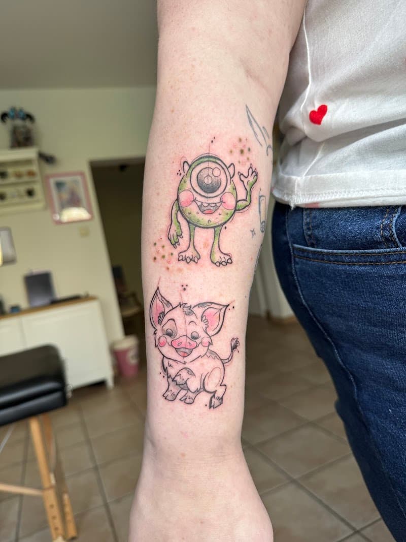 Schetsmatige tattoos van Mike Wazowski en Pua op onderarm.