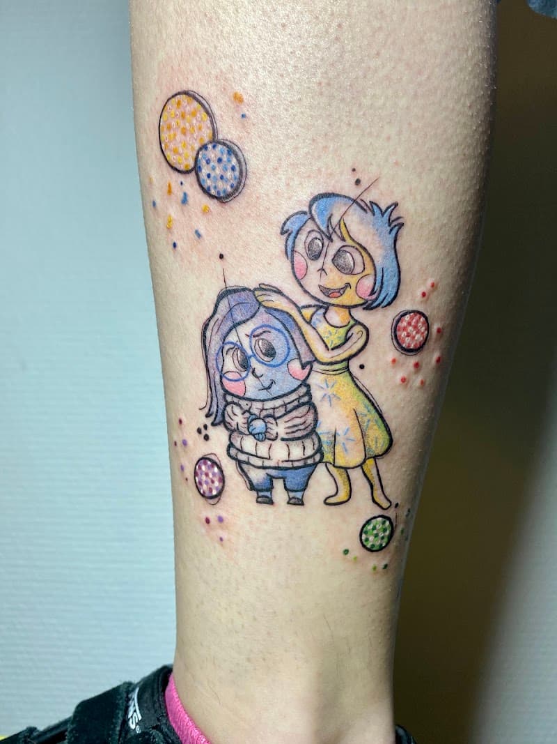 Kleurrijke tattoo van Joy en Sadness uit Inside Out op onderbeen.