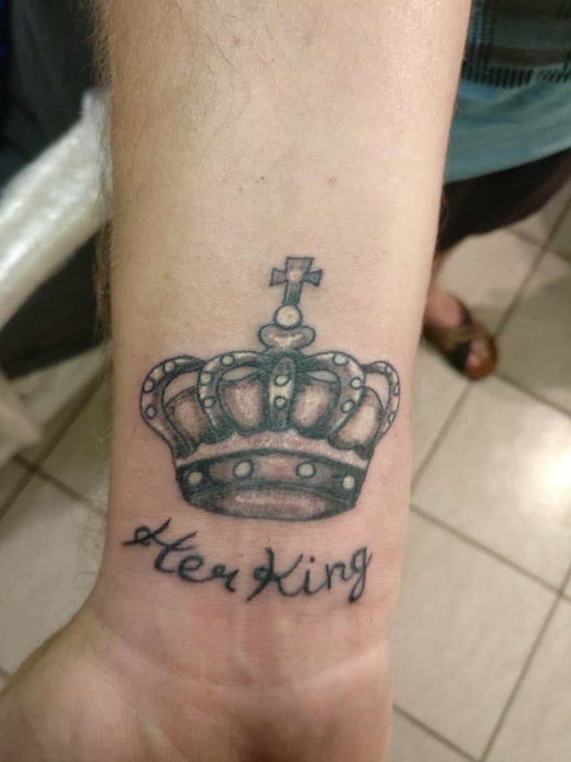 Kroon tattoo met 'Her King' tekst op de pols.