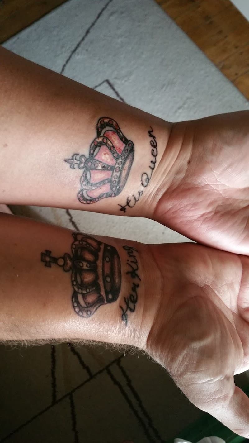 Twee bijpassende kroon tattoos op polsen met tekst 'His Queen' en 'Her King'.