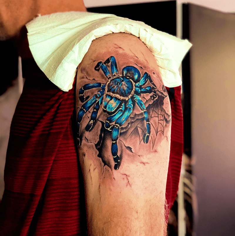 Realistische blauwe tarantula die uit de huid breekt op de bovenarm.