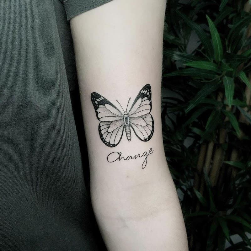 Fineline vlinder met 'Change' tekst op bovenarm.