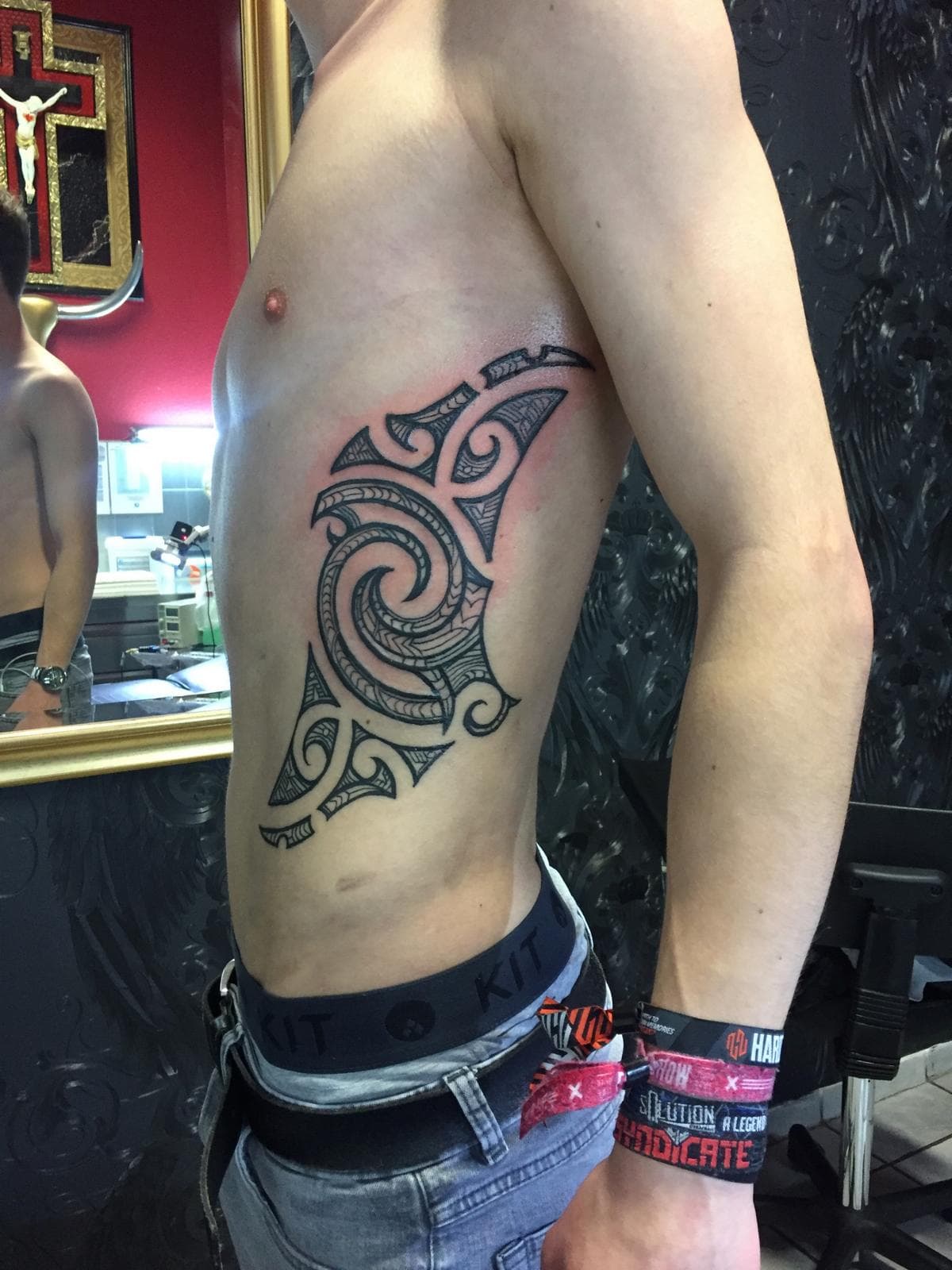 Grote zwarte tribal tattoo met spiraal op de ribben.