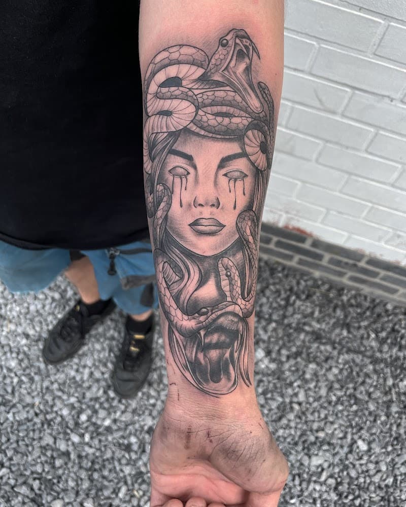 Zwart-wit Medusa tattoo met slangenhaar en tranen op onderarm.