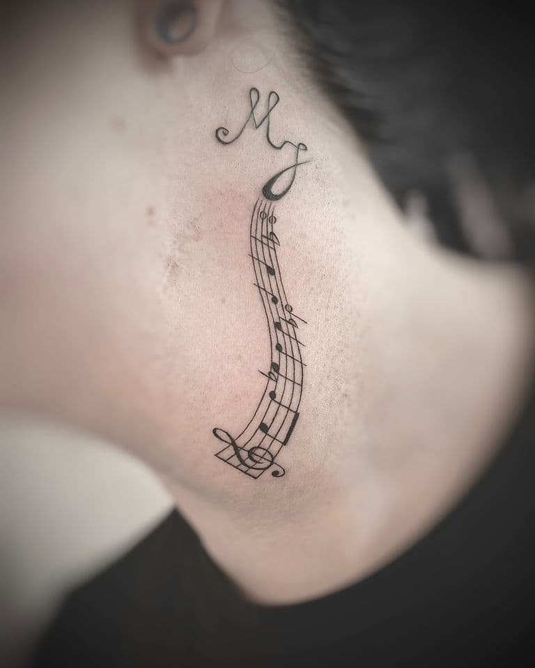 Fineline tattoo van een muziekbalk met noten en initialen 'MJ' in de nek.