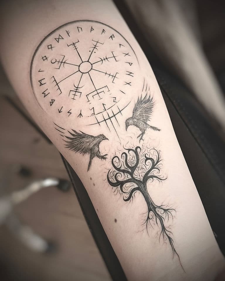 Blackwork tattoo met Vegvisir, runen, twee raven en een levensboom op de onderarm.