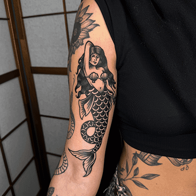 Traditionele zeemeermin tattoo op bovenarm.