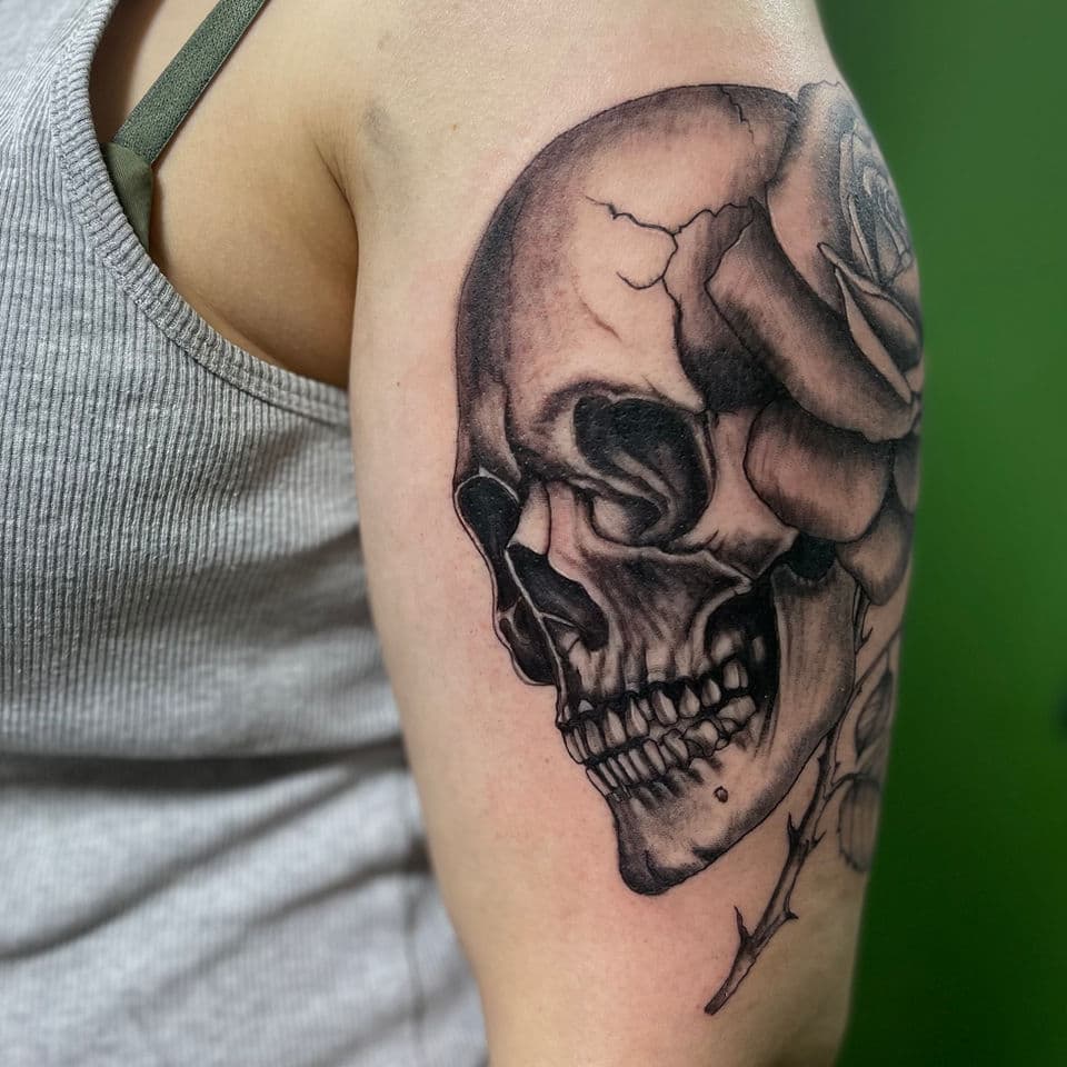 Blackwork schedel met roos op bovenarm.