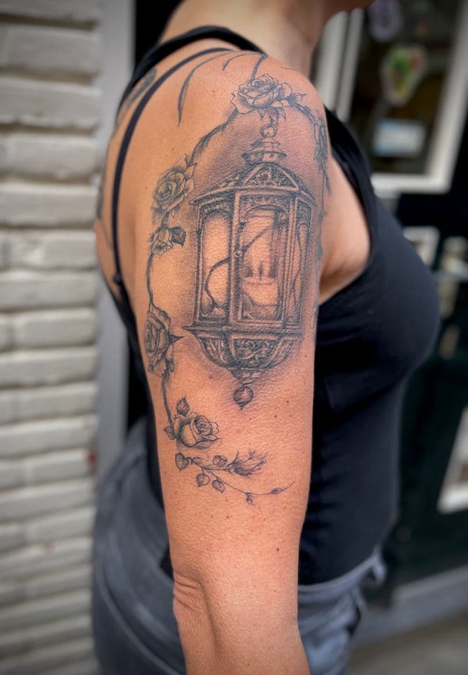 Gedetailleerde lantaarn met kaars en rozen op bovenarm.