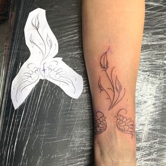 Fineline bloemmotief en vleugels op onderarm, vers gezet.