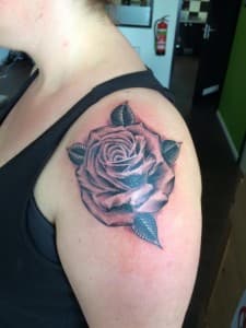 Zwart-wit roos met bladeren op de schouder.