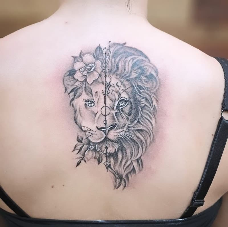 Gesplitste leeuw en leeuwin tattoo met bloemen en geometrische pijl op de rug.