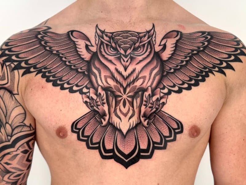 Grote uil met gespreide vleugels op de borst, in dotwork en blackwork stijl.