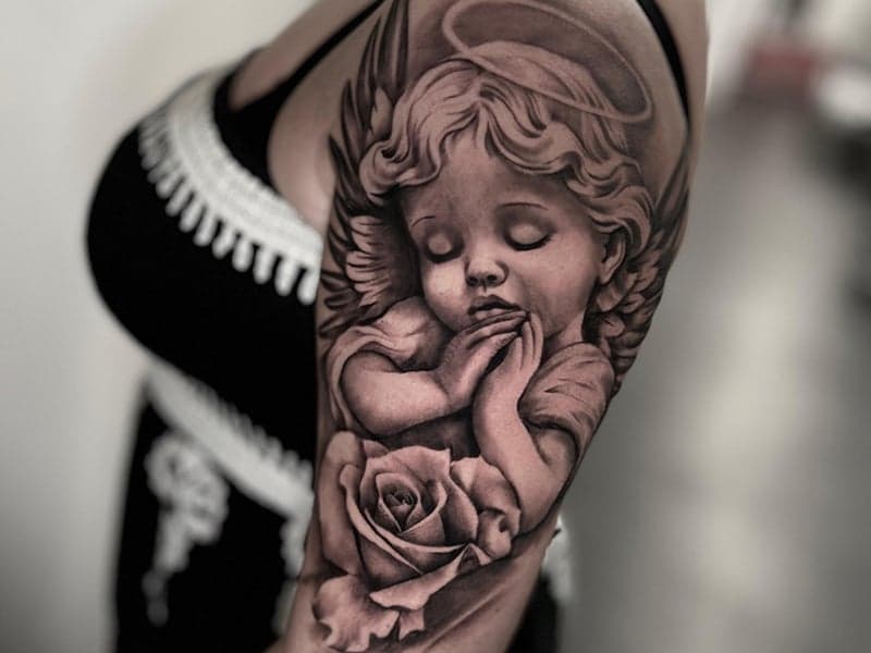 Realistische cherubijn engel met roos op bovenarm.