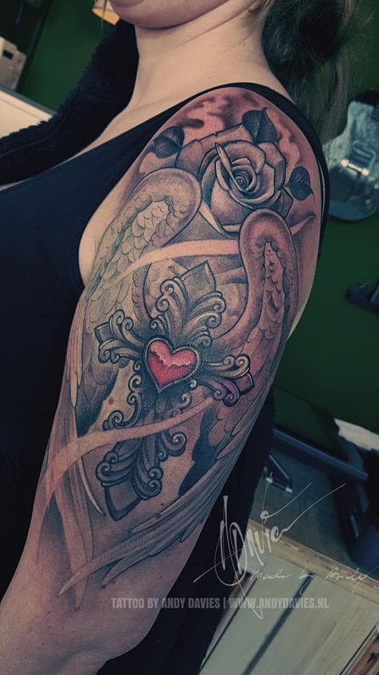 Groot kruis met rood hart, vleugels en roos op bovenarm.