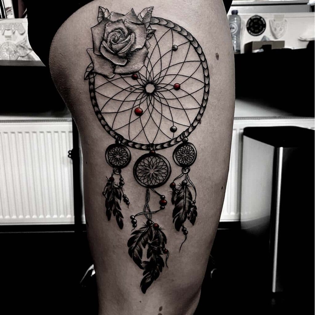 Grote dromenvanger met roos en veren op bovenbeen.