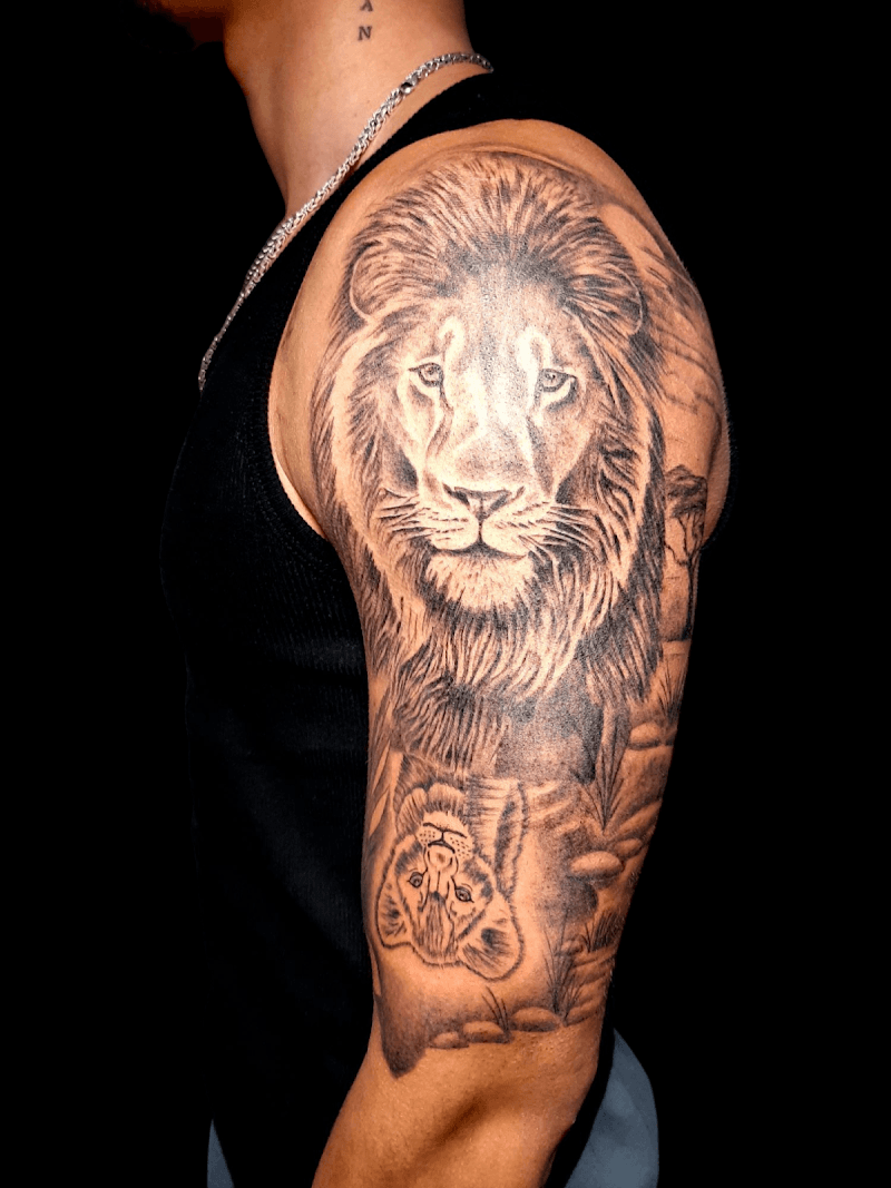 Realistische leeuw en welp tattoo op bovenarm.