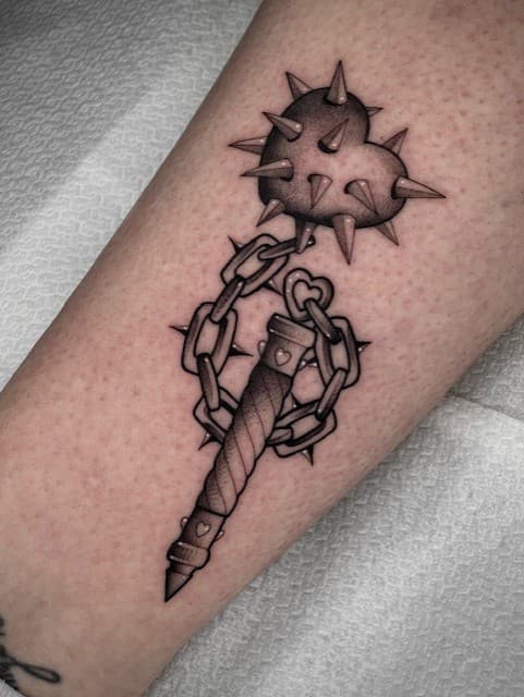 Blackwork tattoo van een strijdvlegel met een gestekeld hart en ketting.