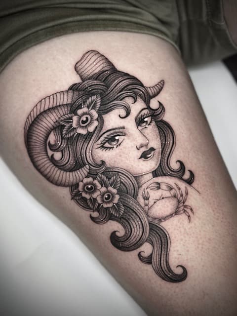 Zwart-wit tattoo van vrouw met ramshoorns, bloemen en een krab.