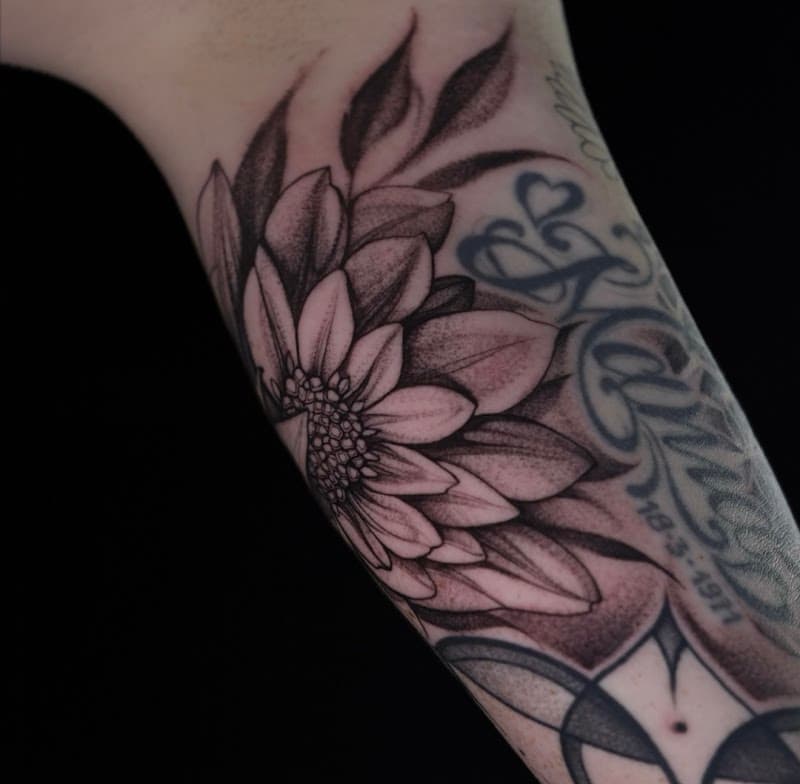 Blackwork bloem tattoo met dotwork schaduw op de onderarm.