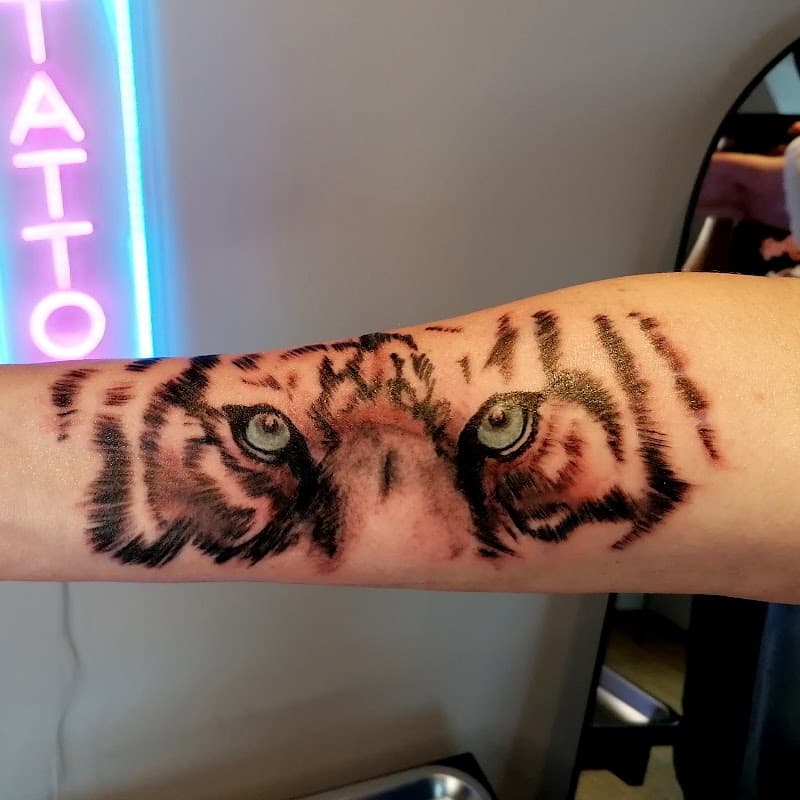Realistische tijgerogen tattoo op onderarm.
