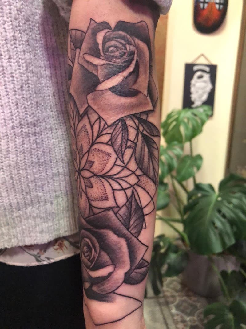 Zwart-wit tattoo van twee rozen en een geometrische mandala op de onderarm.