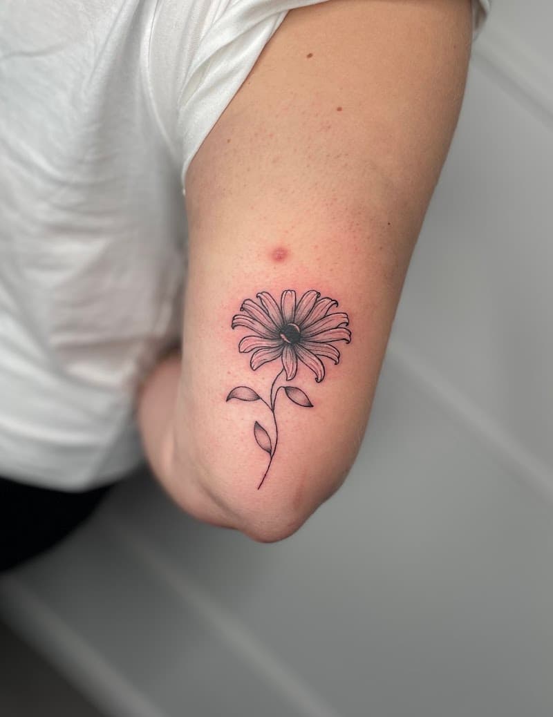 Fineline bloem tattoo op de bovenarm.