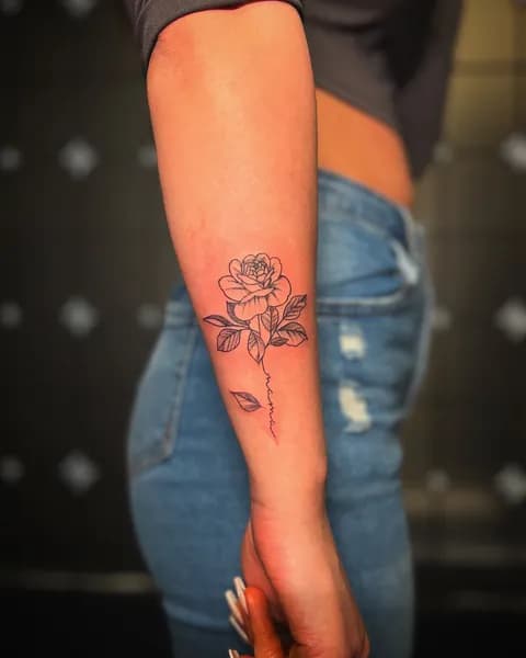 Fineline roos met 'mama' in de steel op onderarm.