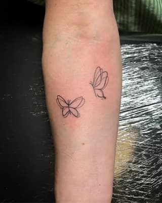 Twee minimalistische fineline vlinders op de onderarm.