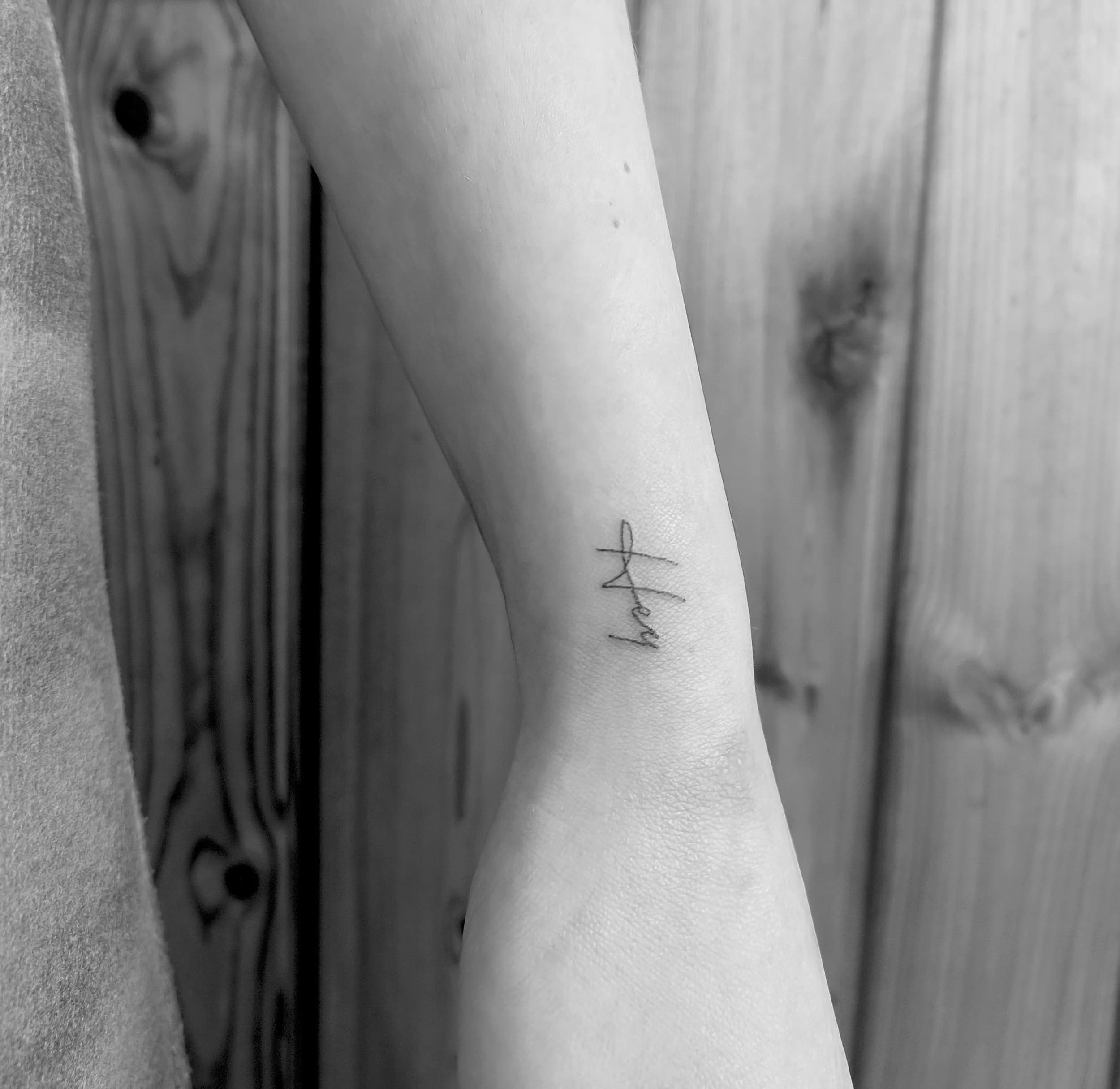 Kleine fineline 'Hey' tekst tattoo op de pols.