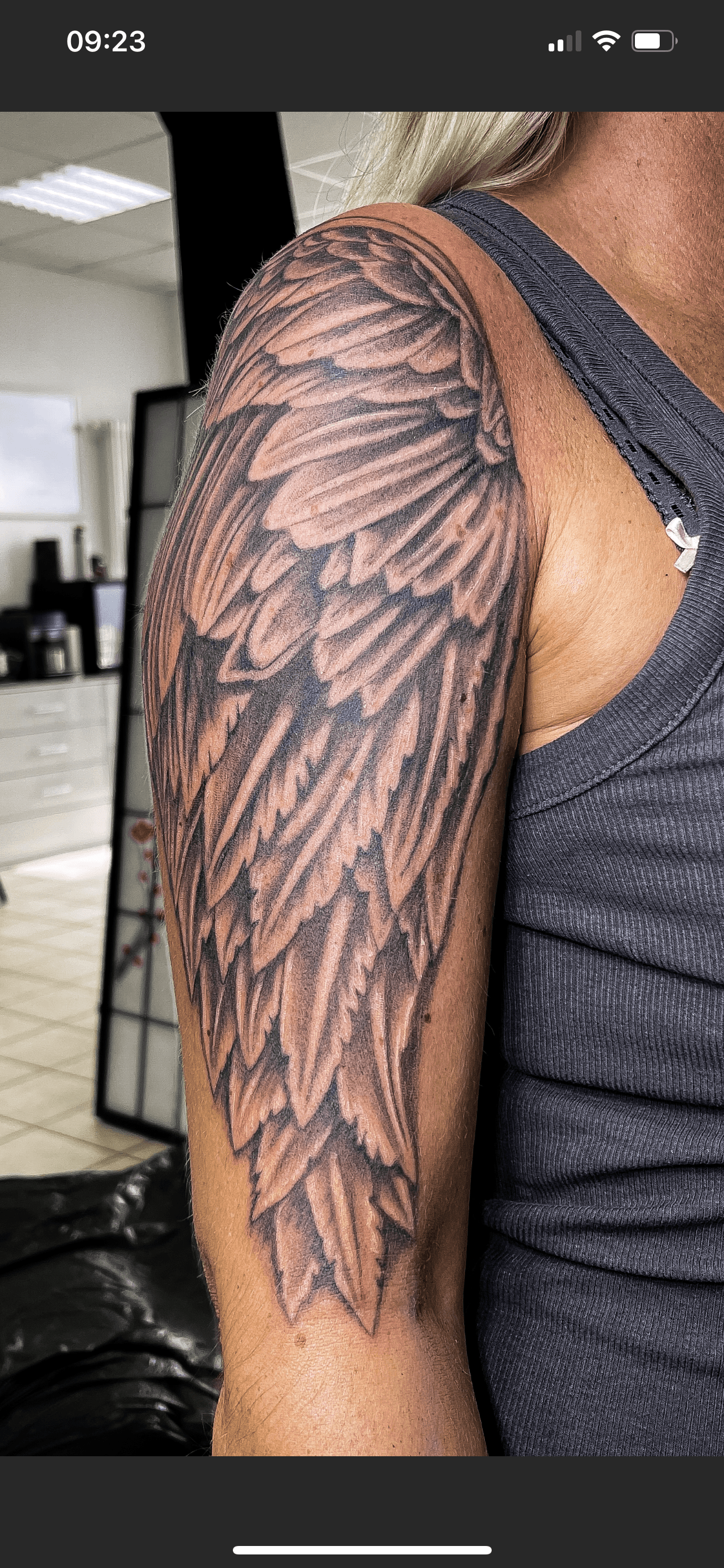 Grote, realistische vleugel tattoo op de bovenarm.