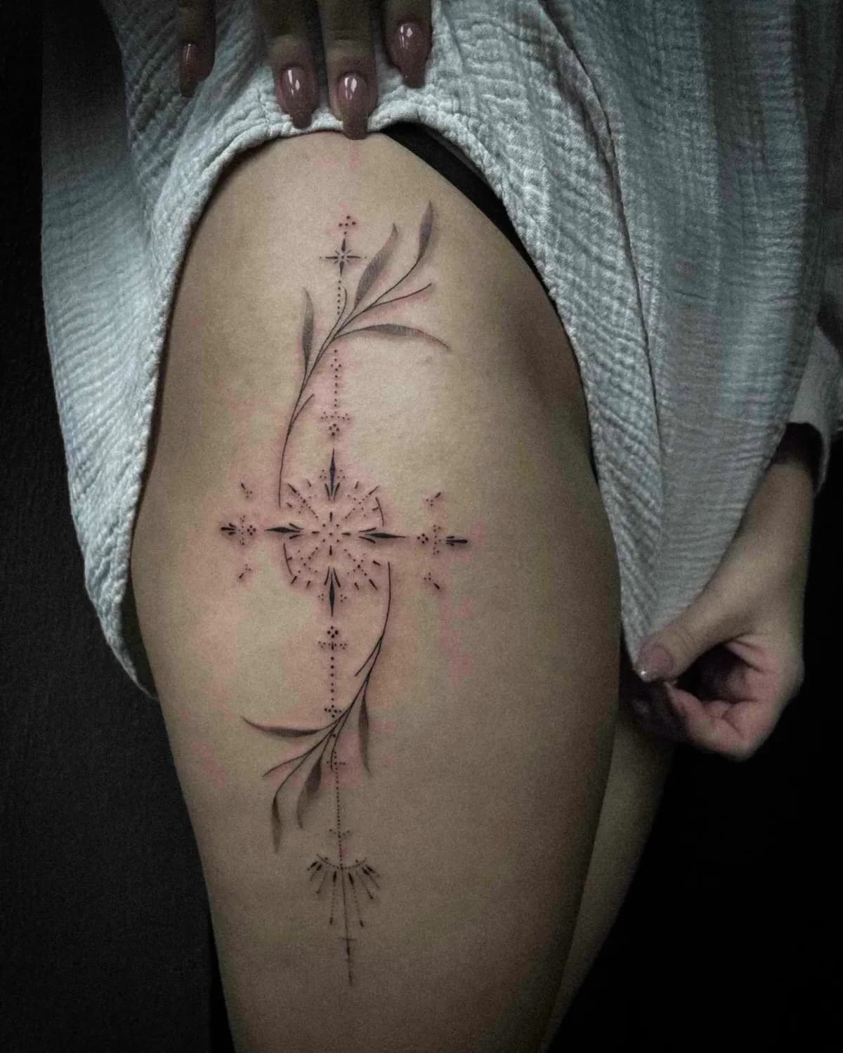 Fineline en dotwork tattoo met geometrische vormen en bladeren op het bovenbeen.