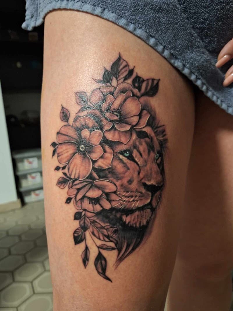 Realistische leeuwenkop met bloemen op bovenbeen.