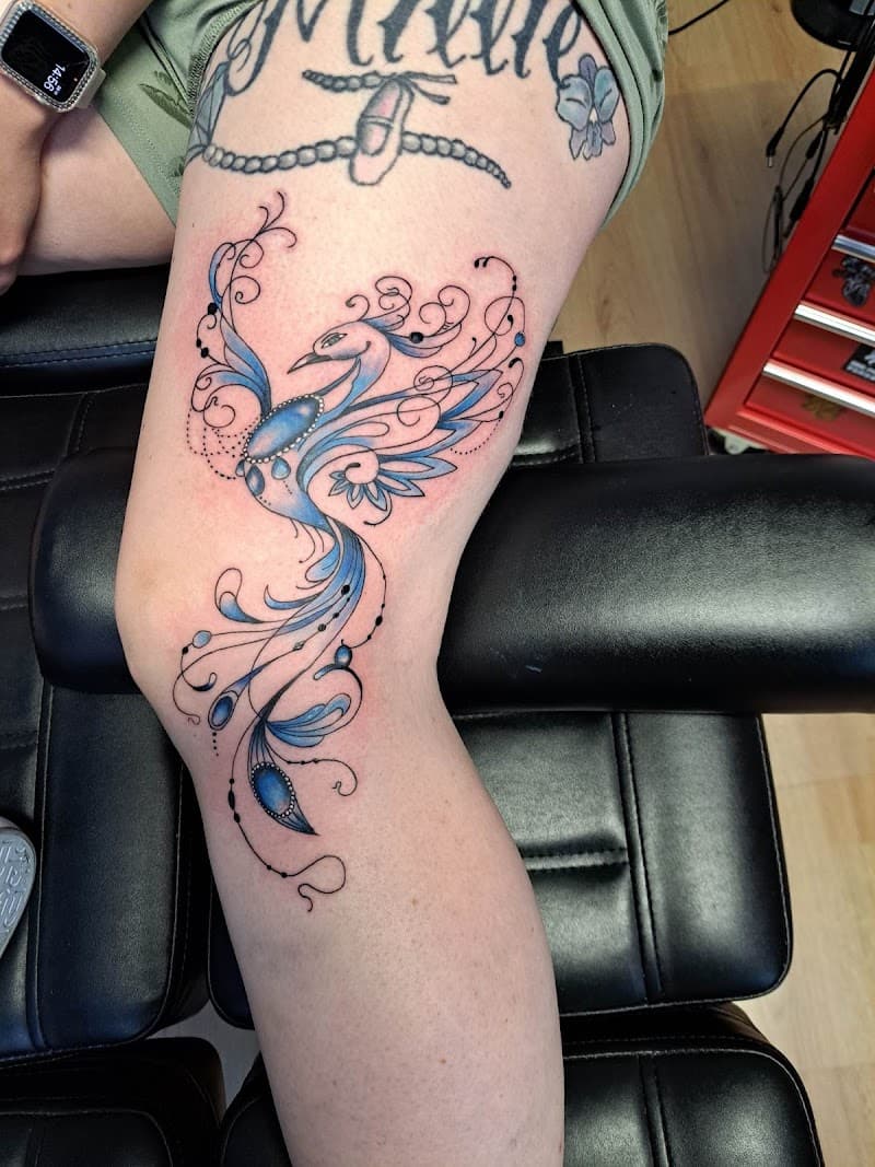 Sierlijke blauwe feniks tattoo met dotwork op bovenbeen.