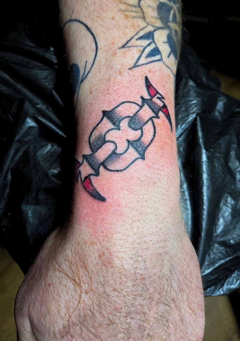 Tribal-stijl symbool met rode accenten op de pols.